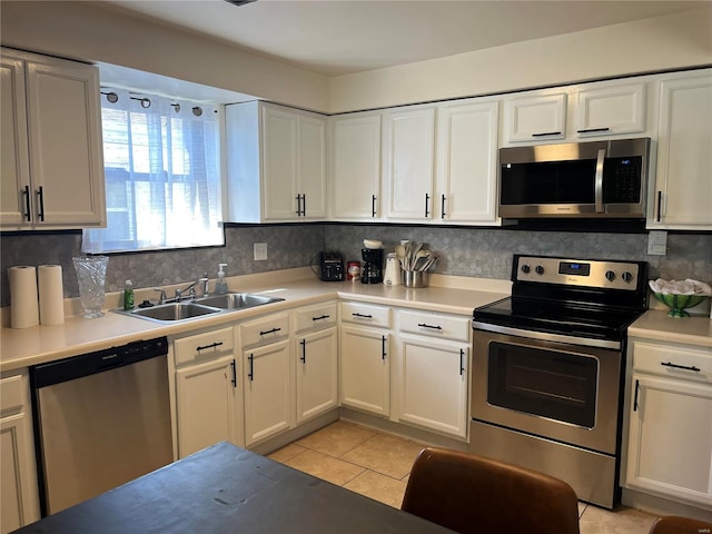 kitchen featuring backsplash, appliances with stainless steel finishes, white cabinets, and a sink