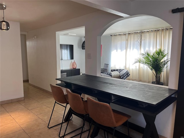 dining room with light tile patterned flooring, baseboards, and arched walkways