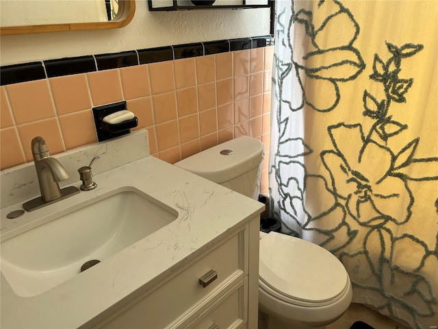 bathroom featuring vanity, toilet, tile walls, and a textured wall