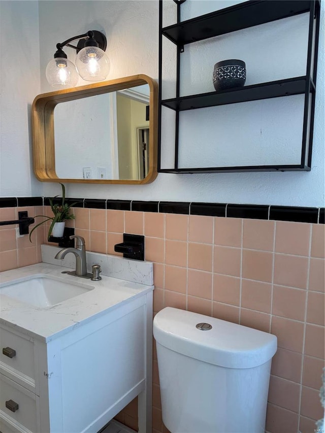 bathroom with toilet, tile walls, and vanity