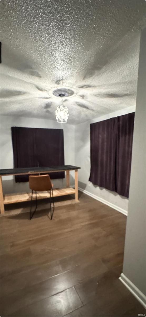 interior space with wood finished floors, baseboards, and a textured ceiling