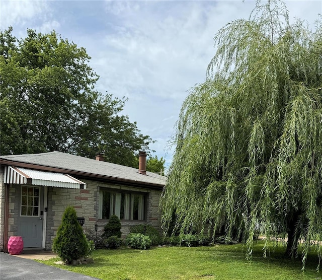 exterior space featuring stone siding, a lawn, and a chimney