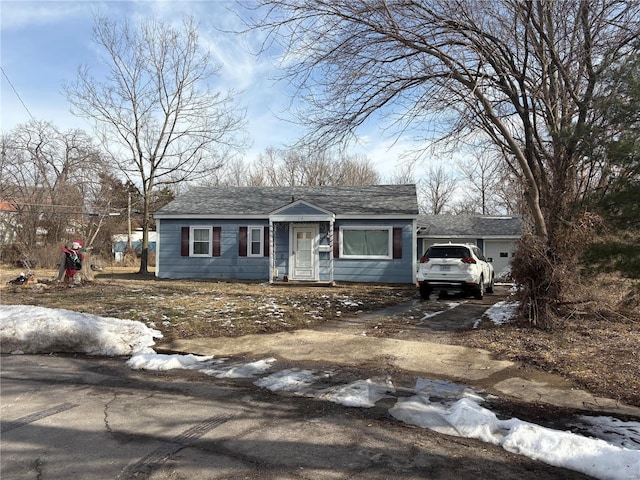 view of front of property featuring driveway, a garage, and roof with shingles