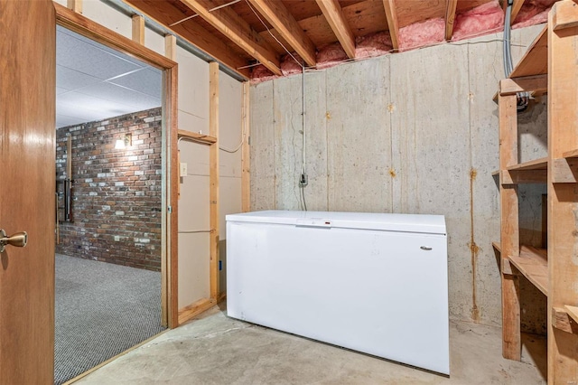 unfinished below grade area with brick wall and refrigerator