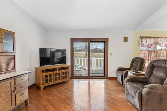 living area with lofted ceiling, light wood-style floors, and baseboards