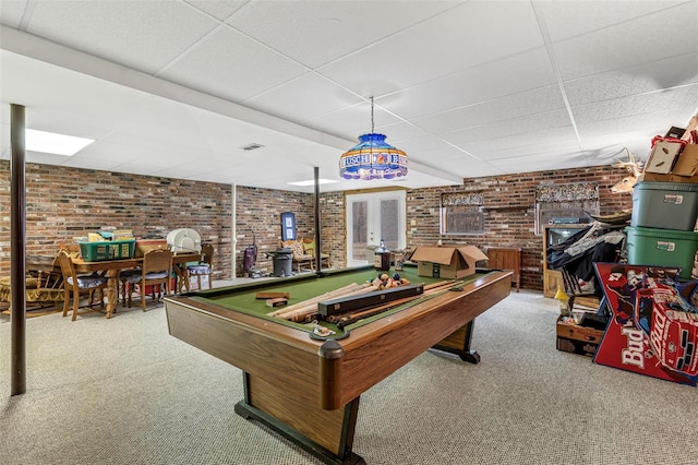 game room featuring brick wall, a drop ceiling, and carpet flooring