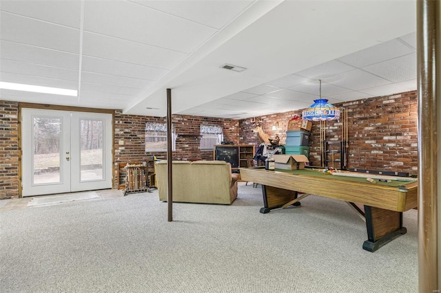 living room with a paneled ceiling, french doors, carpet, and brick wall