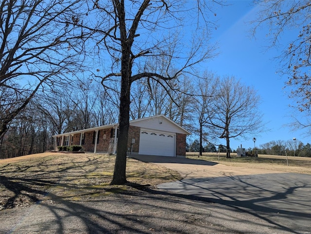 view of front of property featuring brick siding, driveway, and an attached garage