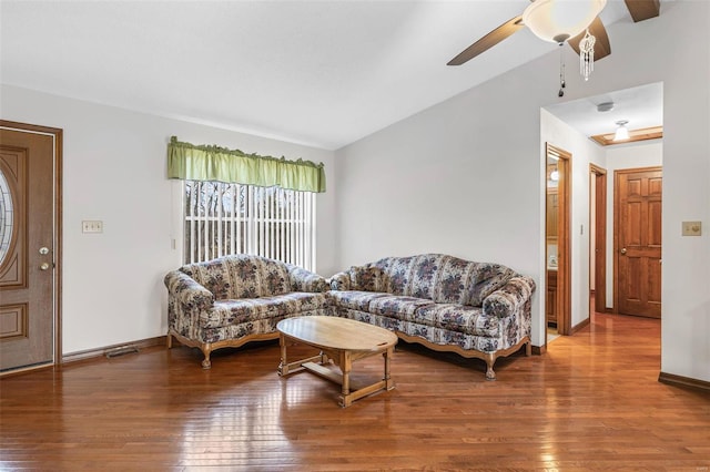 living area with wood-type flooring, vaulted ceiling, baseboards, and ceiling fan