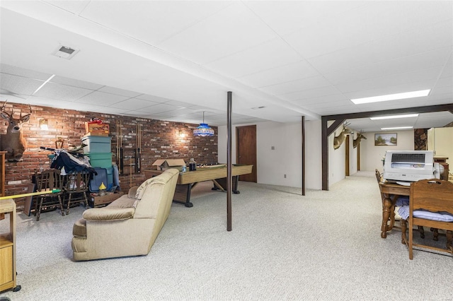 interior space with visible vents, brick wall, carpet flooring, and a paneled ceiling