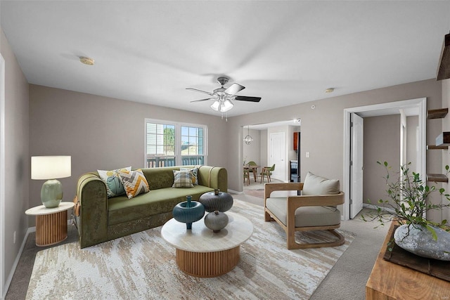 living area with carpet flooring, baseboards, and a ceiling fan