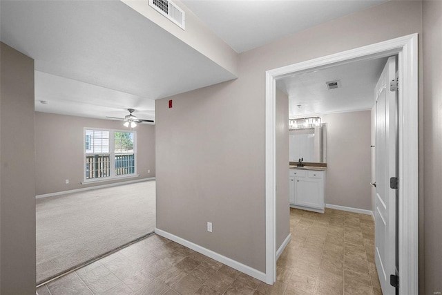 corridor with visible vents, light colored carpet, and baseboards