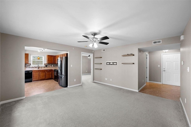 unfurnished living room with visible vents, light colored carpet, baseboards, and ceiling fan