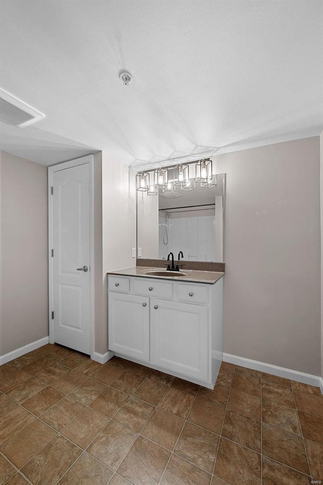 bathroom featuring visible vents, a textured ceiling, vanity, and baseboards