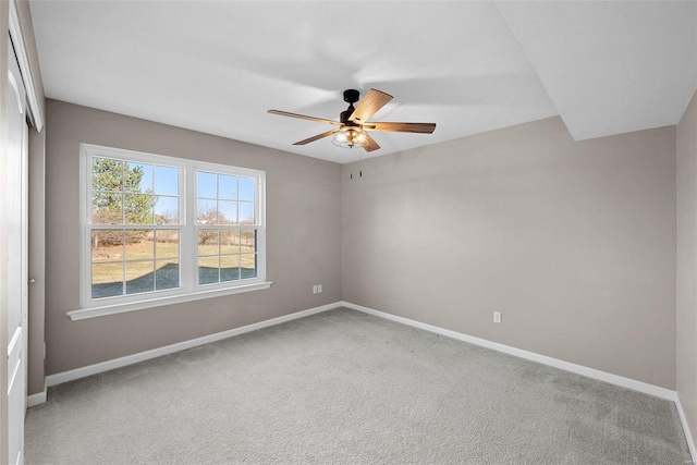 unfurnished room featuring light colored carpet, a ceiling fan, and baseboards