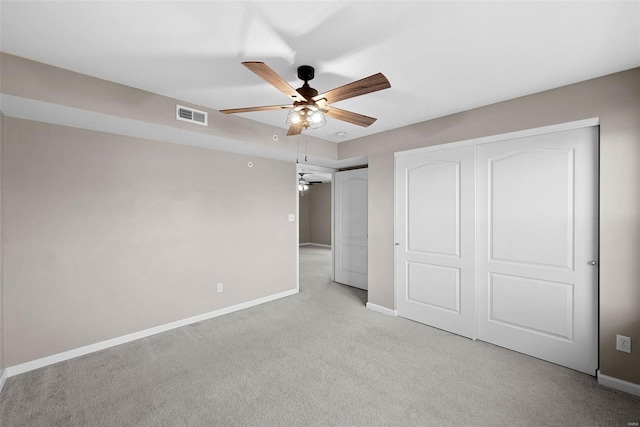 unfurnished bedroom featuring visible vents, a closet, baseboards, light colored carpet, and ceiling fan