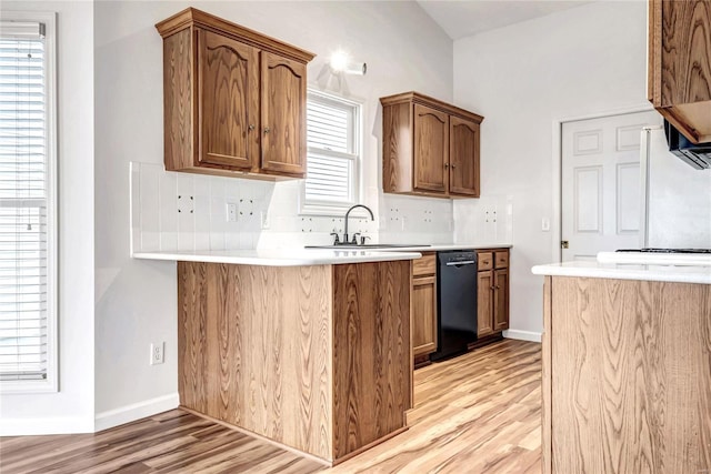 kitchen featuring decorative backsplash, dishwasher, light wood-style flooring, light countertops, and a sink