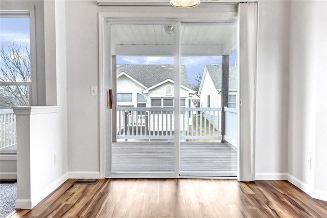 doorway with wood finished floors, visible vents, and baseboards