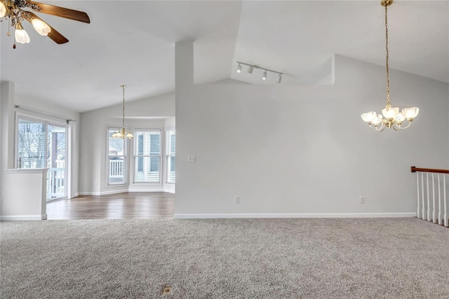 carpeted spare room featuring track lighting, lofted ceiling, baseboards, and ceiling fan with notable chandelier