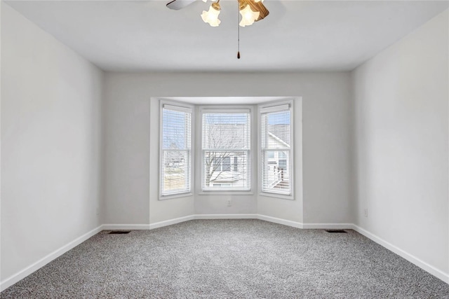 spare room with carpet floors, visible vents, and baseboards