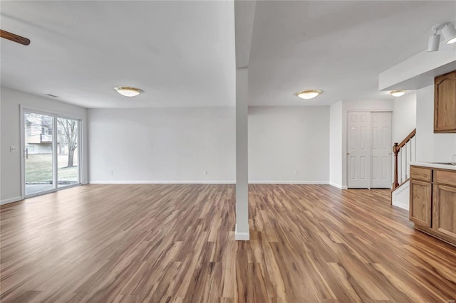 below grade area featuring light wood-style flooring, stairway, and baseboards