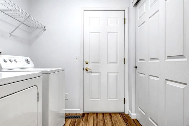 washroom with baseboards, laundry area, wood finished floors, and washer and dryer