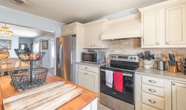 kitchen with stainless steel appliances, custom exhaust hood, cream cabinetry, and visible vents