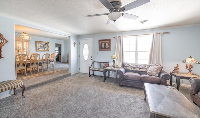 carpeted living room with visible vents, ornamental molding, a ceiling fan, a textured ceiling, and baseboards