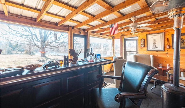 home office with beam ceiling, wood walls, a dry bar, and a ceiling fan