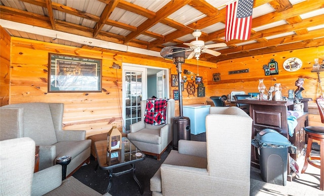 living room with beam ceiling, wooden walls, and ceiling fan