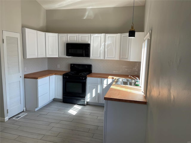 kitchen featuring butcher block counters, a sink, white cabinetry, decorative backsplash, and black appliances