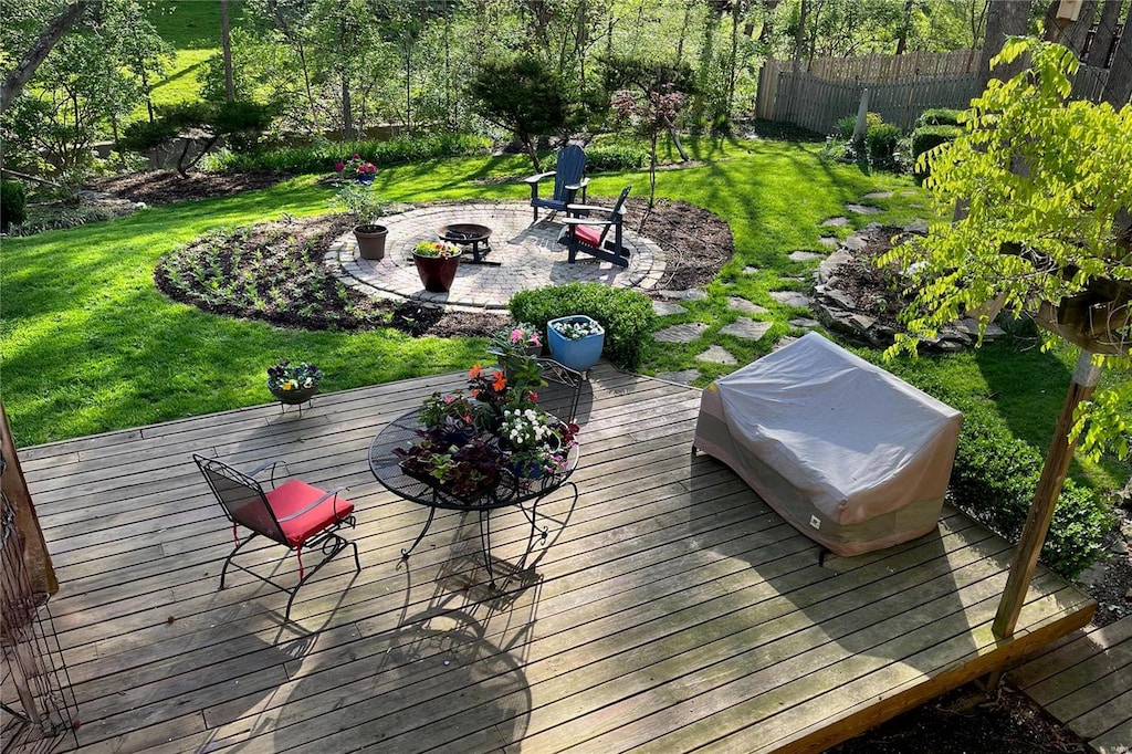 deck featuring a patio area, fence, a fire pit, and a lawn