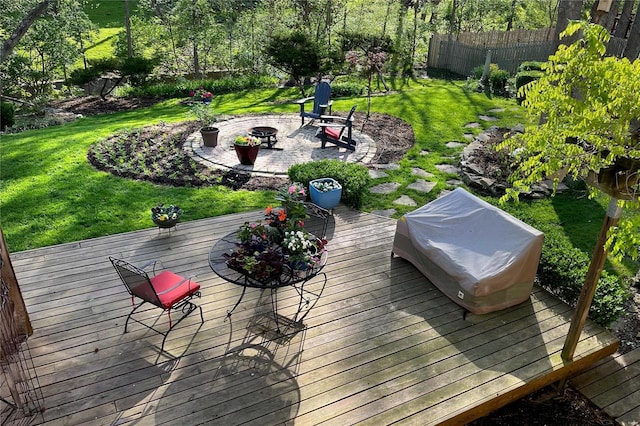 deck featuring a patio area, fence, a fire pit, and a lawn