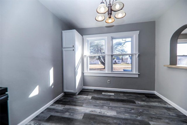 unfurnished dining area with dark wood-style floors, baseboards, and a wealth of natural light