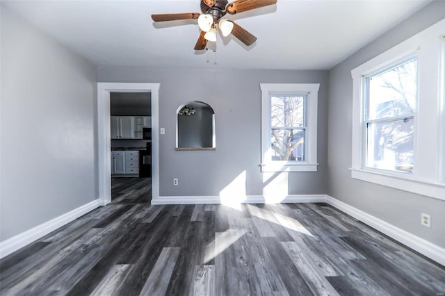 interior space featuring a ceiling fan, baseboards, and dark wood-style flooring