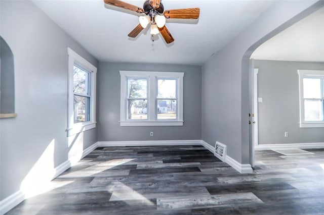 unfurnished room featuring visible vents, arched walkways, baseboards, and wood finished floors