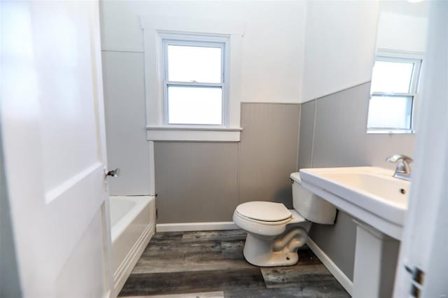 full bathroom featuring a bathtub, a wainscoted wall, toilet, and wood finished floors