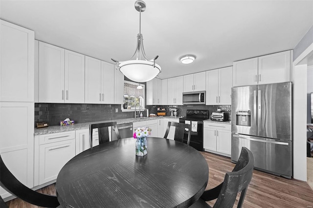 kitchen with dark wood-style flooring, tasteful backsplash, hanging light fixtures, appliances with stainless steel finishes, and white cabinets