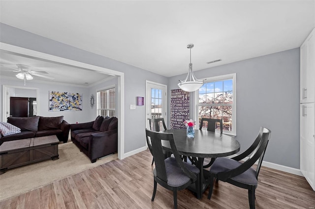 dining space featuring light wood finished floors, baseboards, and visible vents