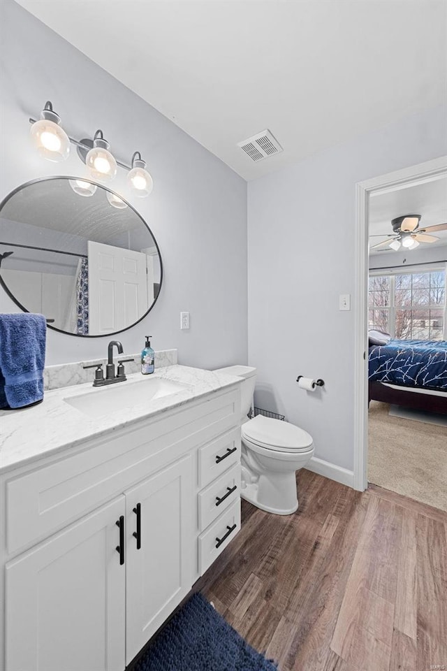 ensuite bathroom featuring baseboards, visible vents, toilet, wood finished floors, and vanity