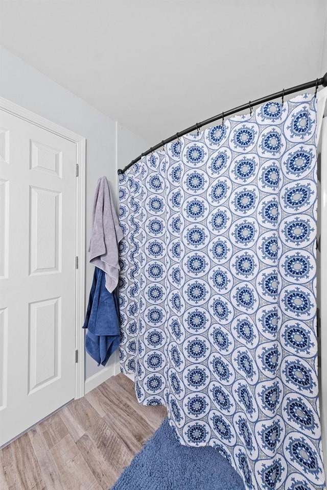 bathroom featuring curtained shower and wood finished floors