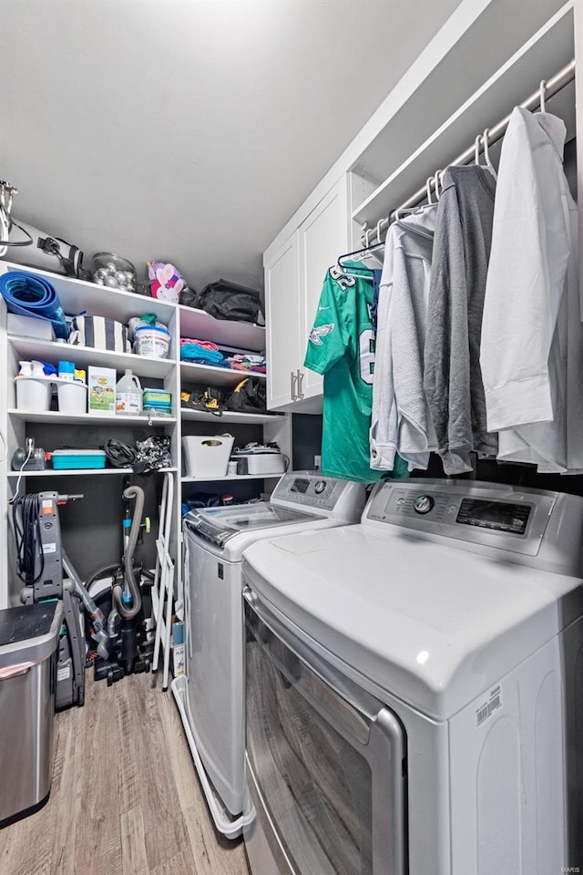 washroom featuring light wood-type flooring, cabinet space, and washer and dryer