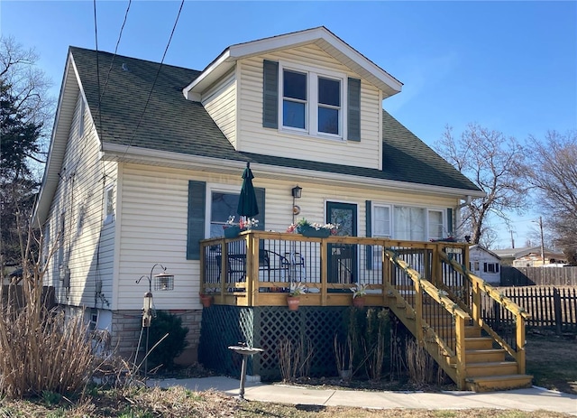 view of front of property with stairs, a deck, roof with shingles, and fence