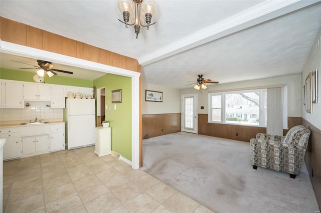 interior space with a wainscoted wall, light carpet, wood walls, a ceiling fan, and beamed ceiling