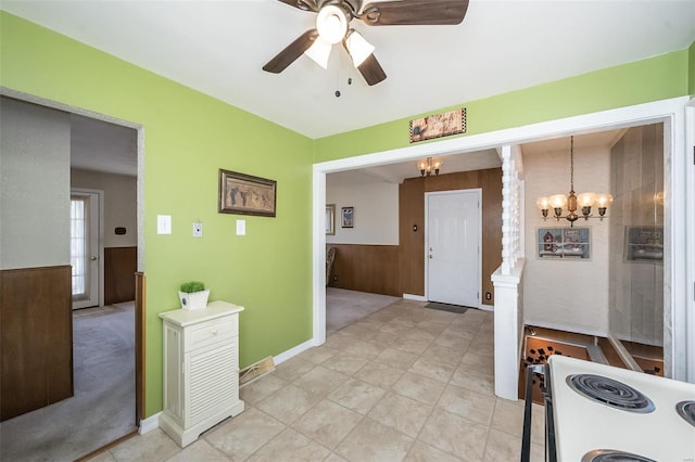 interior space with wooden walls, electric range, and ceiling fan with notable chandelier