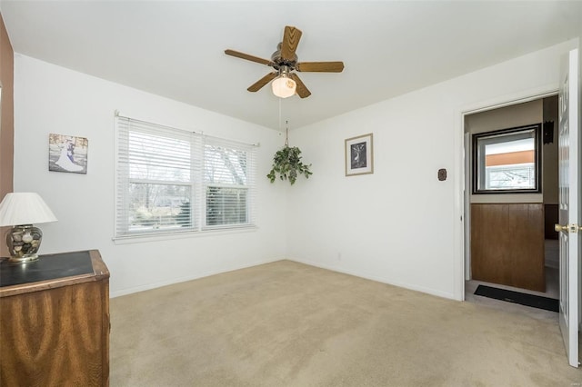 unfurnished room with a ceiling fan, light carpet, and baseboards