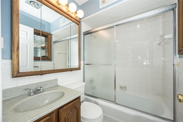 bathroom with bath / shower combo with glass door, decorative backsplash, toilet, vanity, and tile walls