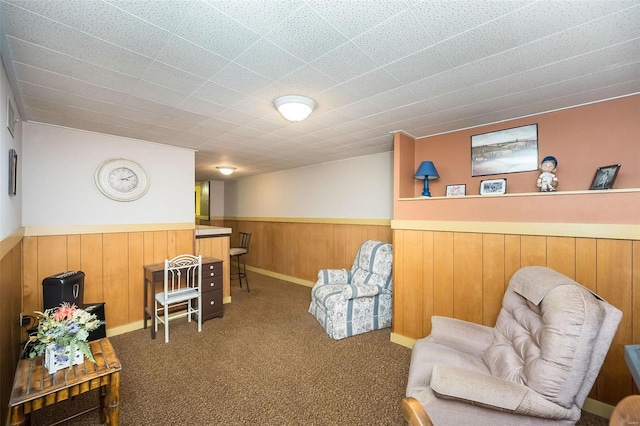 living area featuring wood walls, carpet flooring, and wainscoting