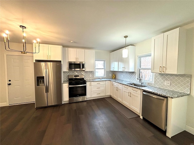 kitchen with white cabinetry, light stone counters, stainless steel appliances, and a sink