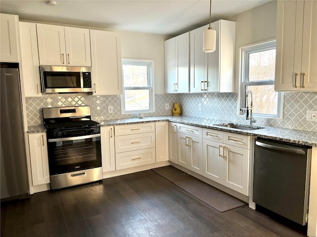 kitchen with light stone counters, stainless steel appliances, a sink, dark wood-style floors, and tasteful backsplash